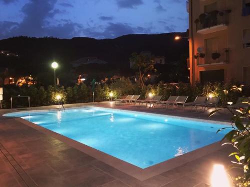 a swimming pool at night with chairs and a building at Hotel Riviera in Deiva Marina