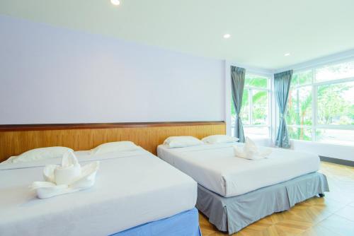 two beds in a room with a window at หาดตื้น คลื่นสวย รีสอร์ท - Hadtuen Kluensuay Resort in Chao Lao Beach