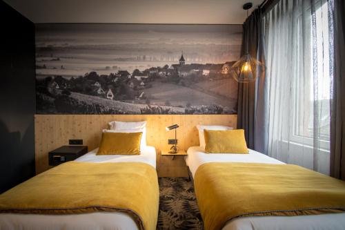 two beds in a room with a painting on the wall at L' Hôtel & Spa Ribeauville- Haut-Koenigsbourg in Ribeauvillé