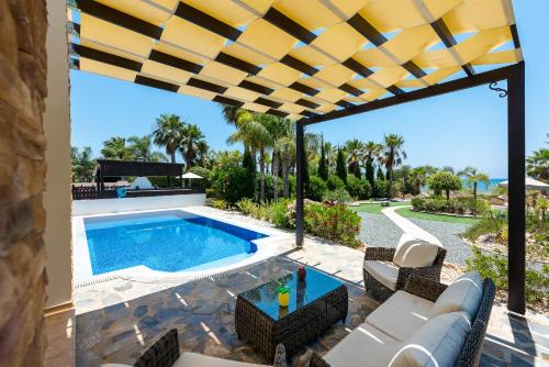 une terrasse avec une piscine, une table et des chaises dans l'établissement Sea Front Costa Blu by Ezoria Villas, à Ayia Napa