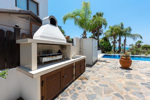 a outdoor kitchen with a grill and a swimming pool at Sea Front Costa Blu by Ezoria Villas in Ayia Napa