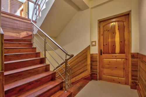 a staircase in a house with wooden walls and a wooden door at Woodstock Inn Manali in Manāli