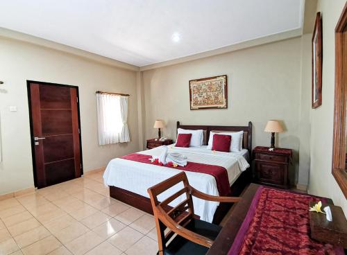 a bedroom with a bed and a chair and a table at Kuta Puri Bungalows, Villas and Resort in Kuta