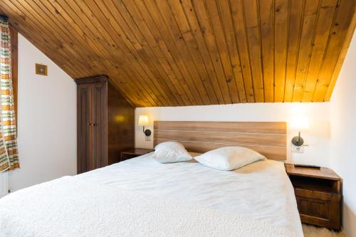 una camera da letto con un letto bianco con un soffitto in legno di Montana Resort Colibita a Colibiţa