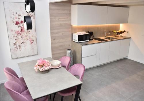 una cucina con un tavolo con sedie rosa e un microonde di Apartments Hidden paradise Rovinj a Rovigno (Rovinj)