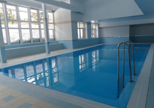 a large swimming pool with blue water in a building at Apartmán ve SkiResortu Poustevník - Pec pod Sněžkou in Pec pod Sněžkou