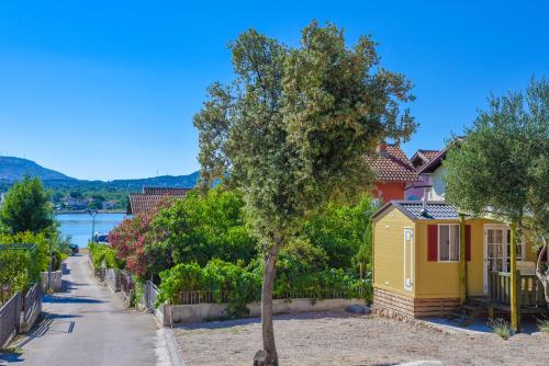 a small yellow house and a tree in a street at Mobile Homes Bilice in Bilice