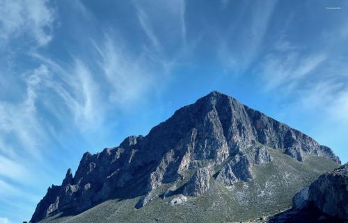 a mountain with a blue sky in the background at Casa Vacanze Libeccio - Villetta con giardino e piscina condominiale in Custonaci