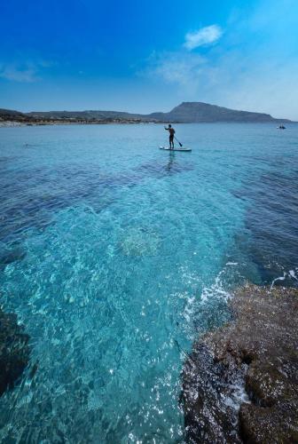 a person on a paddle board in the water at Casa Vacanze Libeccio - Villetta con giardino e piscina condominiale in Custonaci
