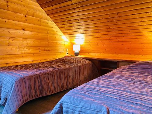 ジェラールメにあるChalet Sapinの木造キャビン内のベッドルーム1室(ベッド2台付)