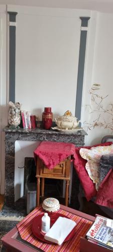 a living room with a table and a fireplace at Chambre d'Hôtes Les Jardins de Marie, SCI Charles III in Bernay