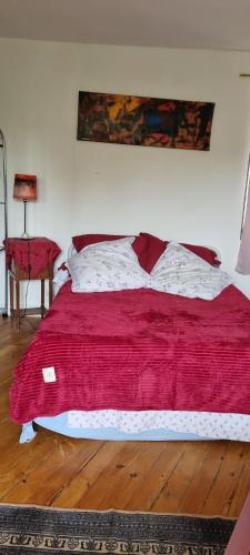 a bedroom with a red bed with a red blanket at Chambre d'Hôtes Les Jardins de Marie, SCI Charles III in Bernay