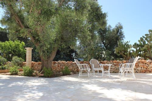 a group of chairs and a table in front of a stone wall at Masseria Zambardo in San Vito dei Normanni