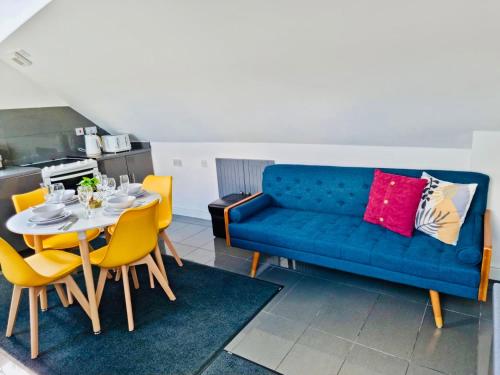 een woonkamer met een blauwe bank en een tafel bij 3 bedroom apartment near Birmingham airport/NEC in Birmingham