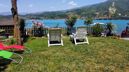 two lawn chairs sitting in the grass near the water at Dina apartman Jablaničko jezero in Konjic