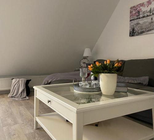 a white coffee table with a vase of flowers on it at FeWo Casa in Boizenburg