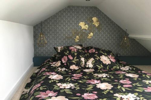 um quarto com uma cama com colcha floral em La petite Brainoise - Gîte avec salle jacuzzi 120 jets em Braine