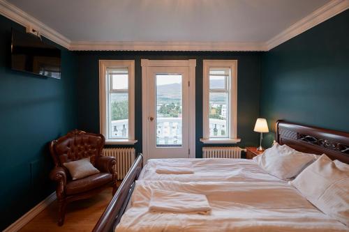 a bedroom with a bed and a chair and windows at Akurinn Residence in Akureyri