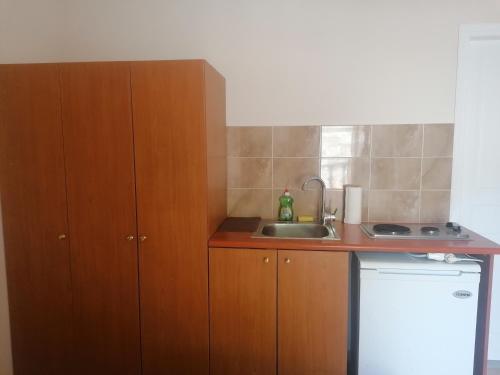 una pequeña cocina con armarios de madera y fregadero en Beach Studio apartment 3, Komi en Chios