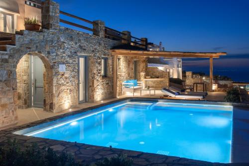 a swimming pool in front of a villa at night at Naxos Rock Villas in Stelida