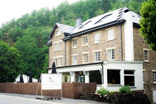 a large brick building with a sign in front of it at Café Coureur Houffalize in Houffalize