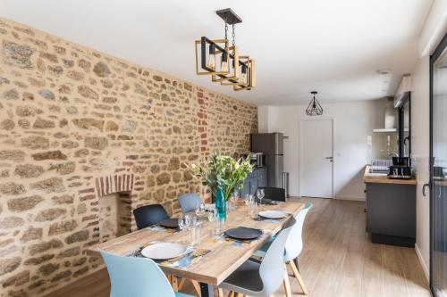 une salle à manger avec un mur en pierre et une table et des chaises en bois dans l'établissement Le Ty Family, à Dinard