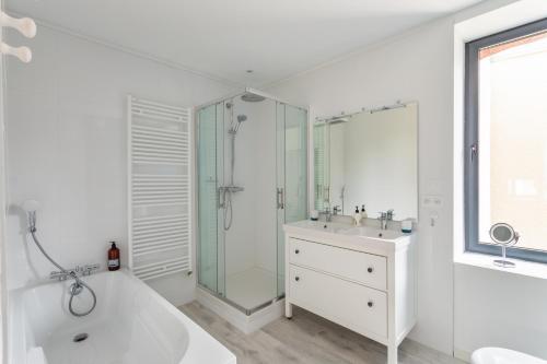 a white bathroom with a tub and a sink and a shower at Le Ty Family in Dinard
