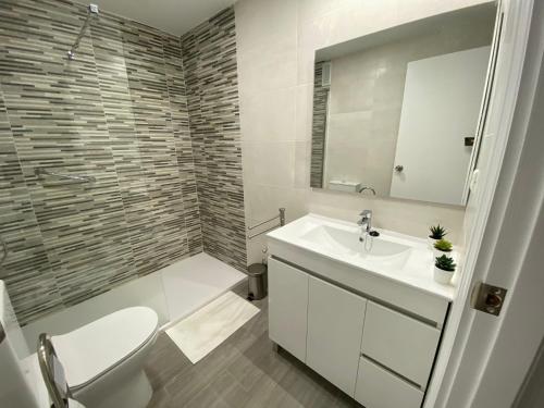 ein Badezimmer mit einem Waschbecken, einem WC und einem Spiegel in der Unterkunft Apartamento en el centro de Estepona in Estepona