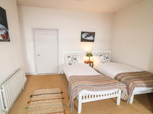 two beds in a room with white walls at The Ferry House in Ramelton