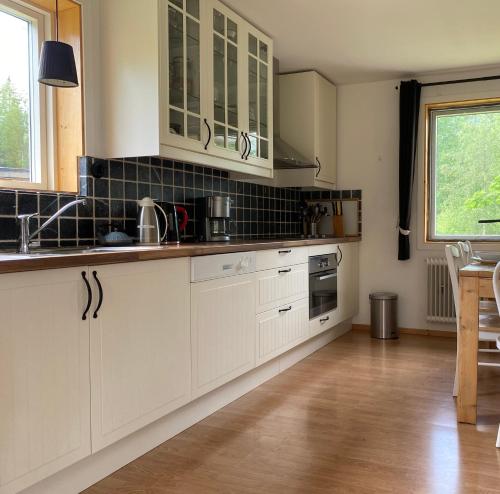 a kitchen with white cabinets and a wooden floor at Nyhyttan Nora Bergslagen The Three Birches in Nora