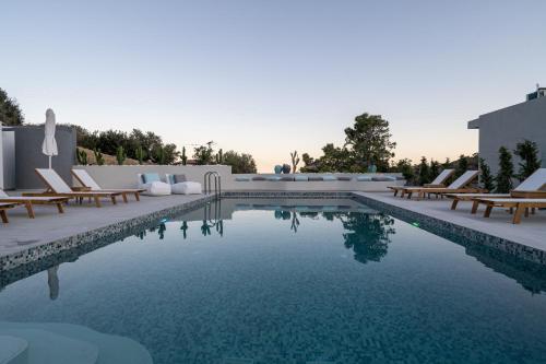 - une piscine entourée de chaises longues et de chaises dans l'établissement Pignolia Suites - Adults Only, à Ierápetra