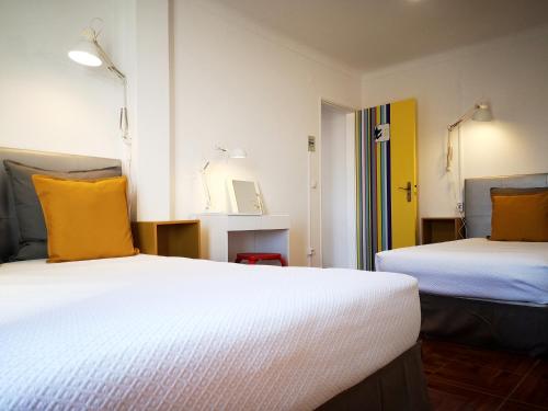 a room with two beds with yellow pillows at Bulldog Inn - Duna Parque Group in Vila Nova de Milfontes