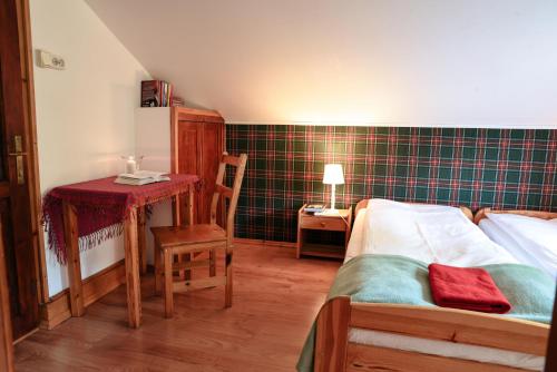 a bedroom with a bed and a table and a chair at Cisówka Pokoje Gościnne in Piwniczna
