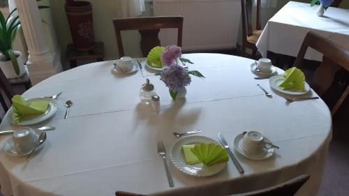 a table with a white tablecloth and a vase of flowers at Pension Marienhof in Kobern-Gondorf