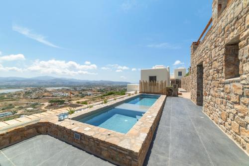 a swimming pool on the side of a stone building at Naxos Rock Villas in Stelida
