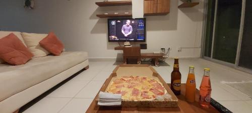 a pizza in a box on a table in a living room at Discoverequador in Tonsupa