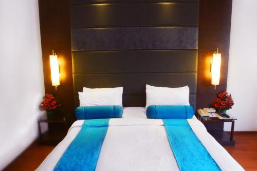 a bedroom with a large bed with blue pillows at Ashraya International Hotel in Bengaluru