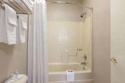 a bathroom with a shower and a tub and a toilet at Baymont by Wyndham Winchester in Winchester