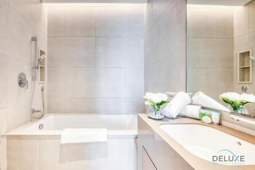 a white bathroom with a tub and a sink at Timeless 1BR at The Address Residences in JBR by Deluxe Holiday Homes in Dubai