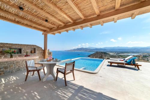 a patio with a table and chairs and a swimming pool at Naxos Rock Villas in Stelida