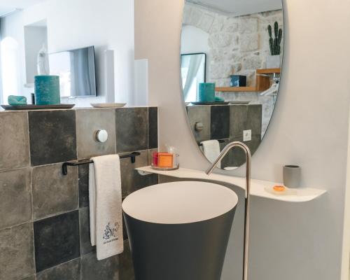 a bathroom with a round sink and a mirror at Antico Mondo Rooms & Suites in Polignano a Mare
