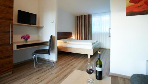 ein Hotelzimmer mit einem Bett und einem Schreibtisch mit einer Flasche Wein in der Unterkunft Gästehaus Weinhandl & Johnnys Pizzeria in Podersdorf am See