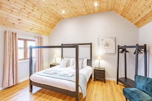 a bedroom with a canopy bed and a chair at Thistle Lodge 21 with Hot Tub in Belladrum
