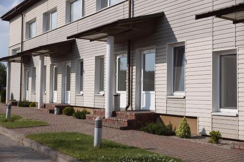 a white house with white columns and a brick driveway at Motelis Gariūnai in Vilnius