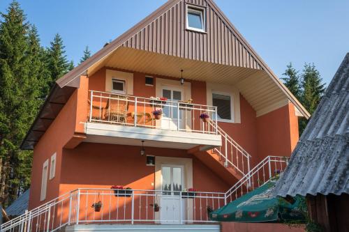 ein orangefarbenes Haus mit einem Balkon und Bäumen in der Unterkunft Apartments Dedeic in Žabljak