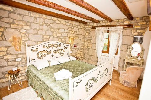 a bedroom with a white bed and a stone wall at Boutique Villa Pucinum in Buzet