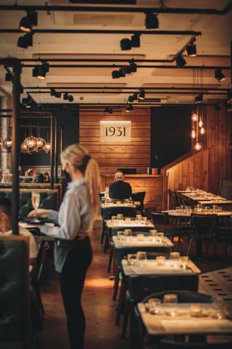 a woman walking inside of a restaurant with tables at Hope Street Hotel in Liverpool