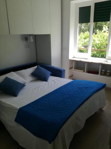 a bedroom with a bed with blue sheets and two windows at La Dépendance di Zio Giovanni in Anacapri