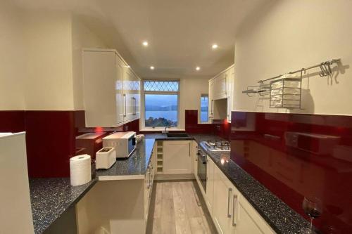 una grande cucina con armadi bianchi e ripiani neri di Beautiful Sea View 2 Bed Home a Port Glasgow