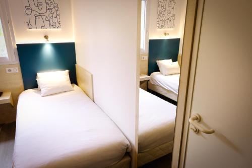 a small room with two beds and a mirror at Kyriad Direct Perpignan Nord - Aéroport in Rivesaltes